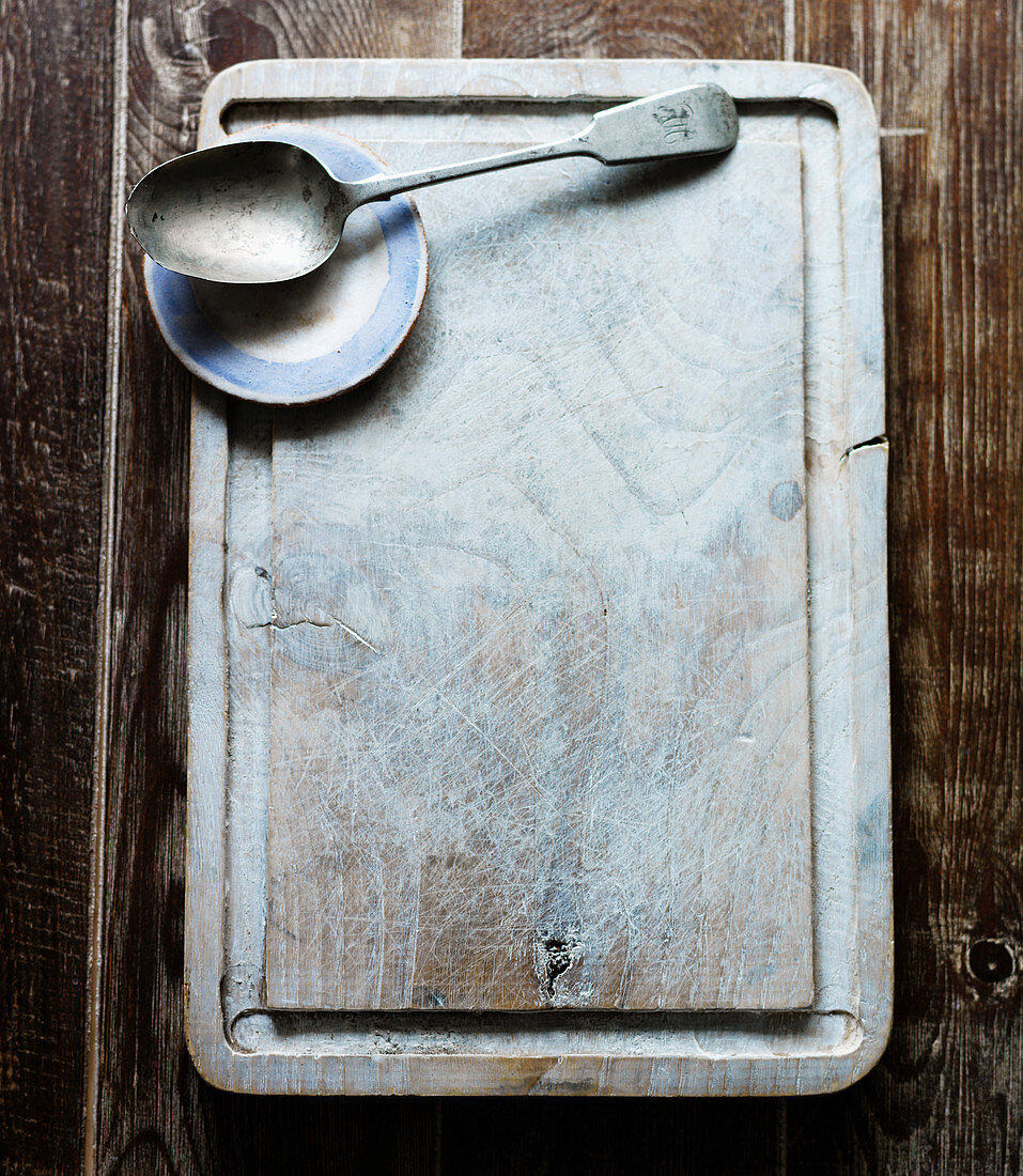 A chopping board with a spoon and a small plate