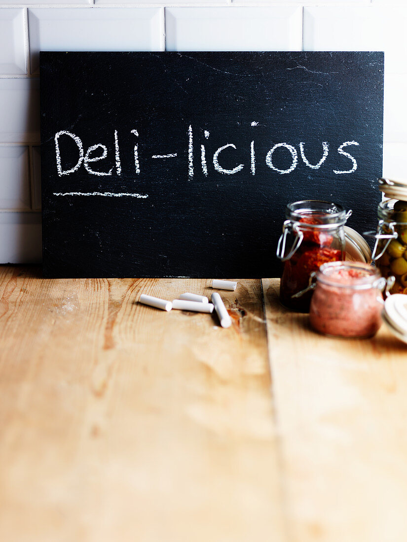 Kreidetafel mit Aufschrift Deli-licious und verschiedene Einmachgläser