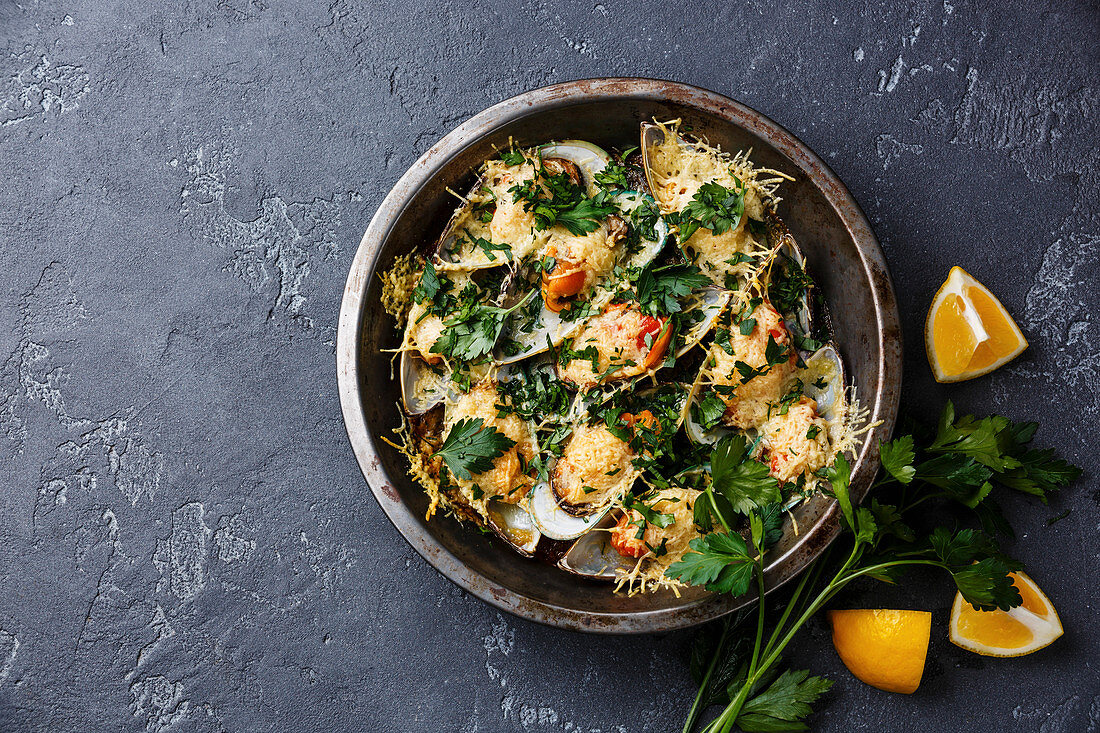 Mussels Clams Kiwi with parmesan cheese in cooking pan on black background