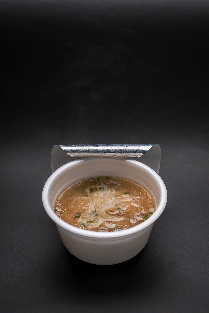 Asian rice noodle soup with vegetables in a plastic cup
