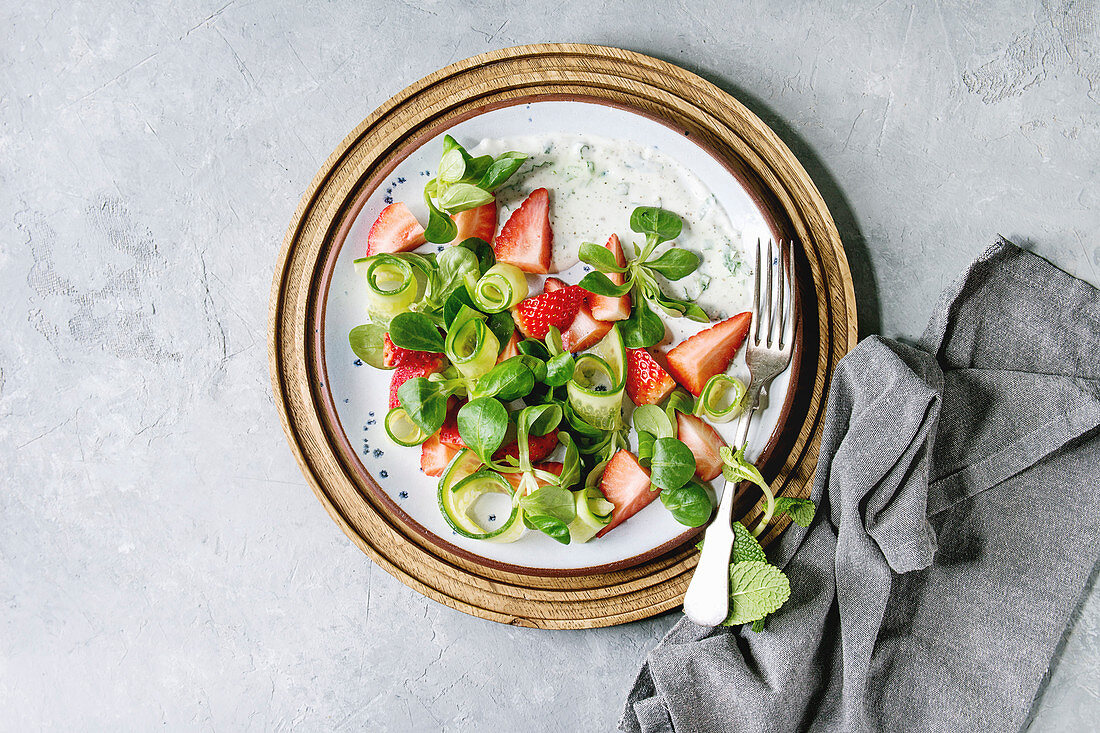 Spring summer diet salad with strawberries, cucumber, green field salad and yogurt mint sauce