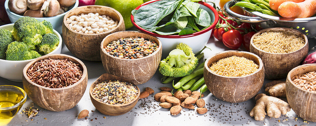 Health food concept with legumes, grains, seeds and organic vegetables on grey concrete background