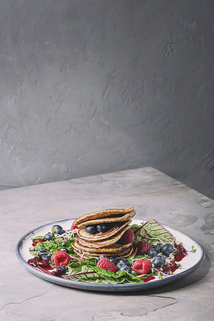 Vegane Kichererbsen-Pancakes auf Salat mit Rote-Bete-Blättern, Sprossen und Beeren