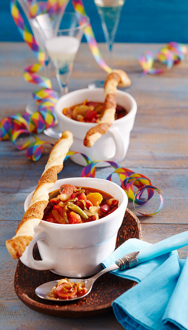 Spicy bean soup with sausages served with yeast dough and puff pastry Parmesan sticks