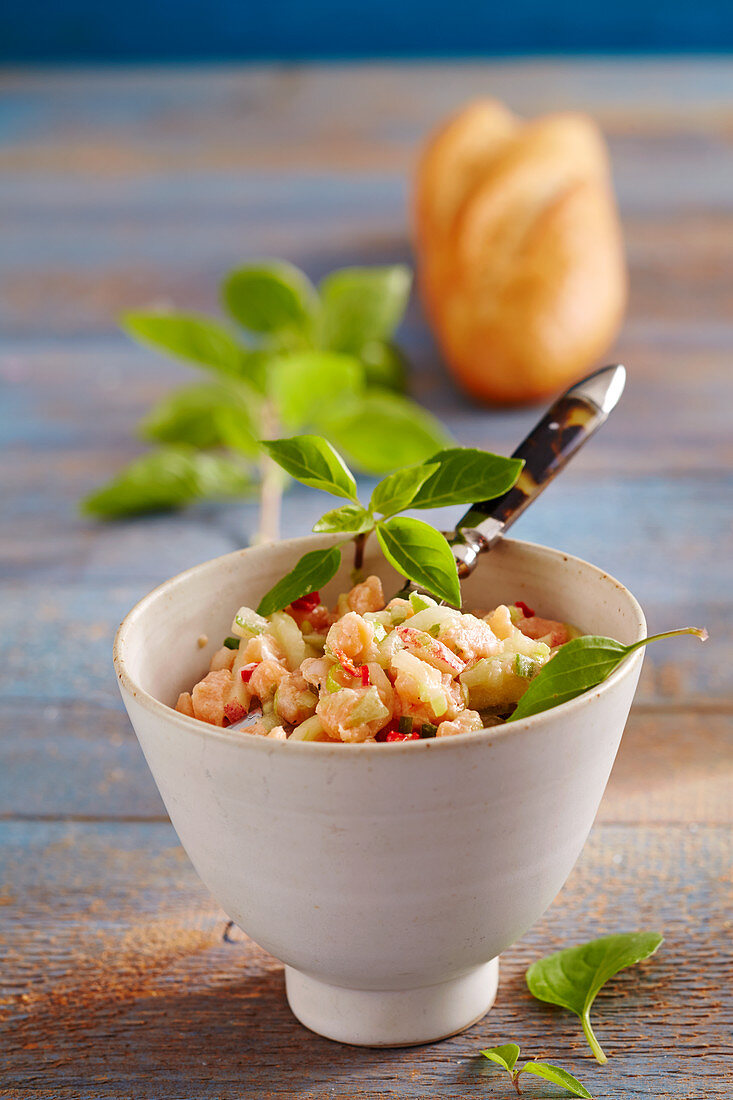 Oriental salmon tartare in a ceramic bowl with baguette