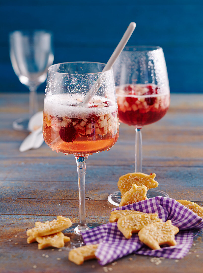 Fruchtige Sylvester-Bowle mit Prosecco und Cranberries im Glas mit pikantem Schweinchengebäck