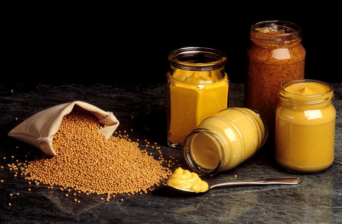 Mustard Seeds Spillng From a Bag; Jars of Prepared Mustard