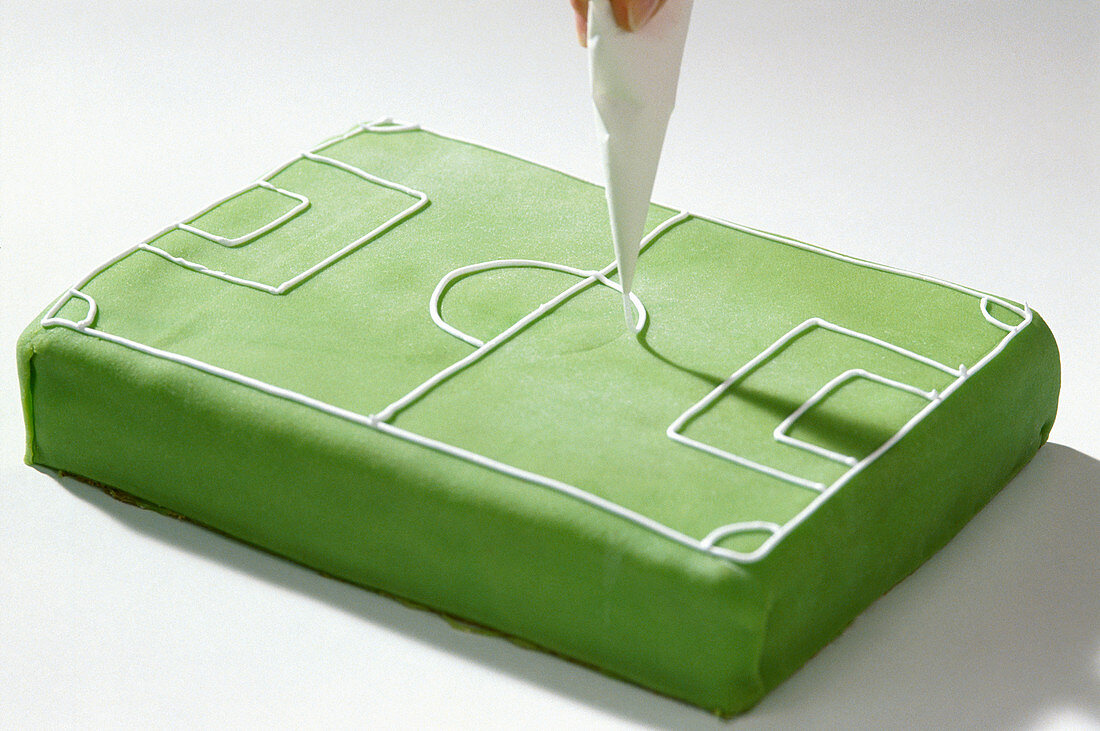 A football pitch cake being decorated