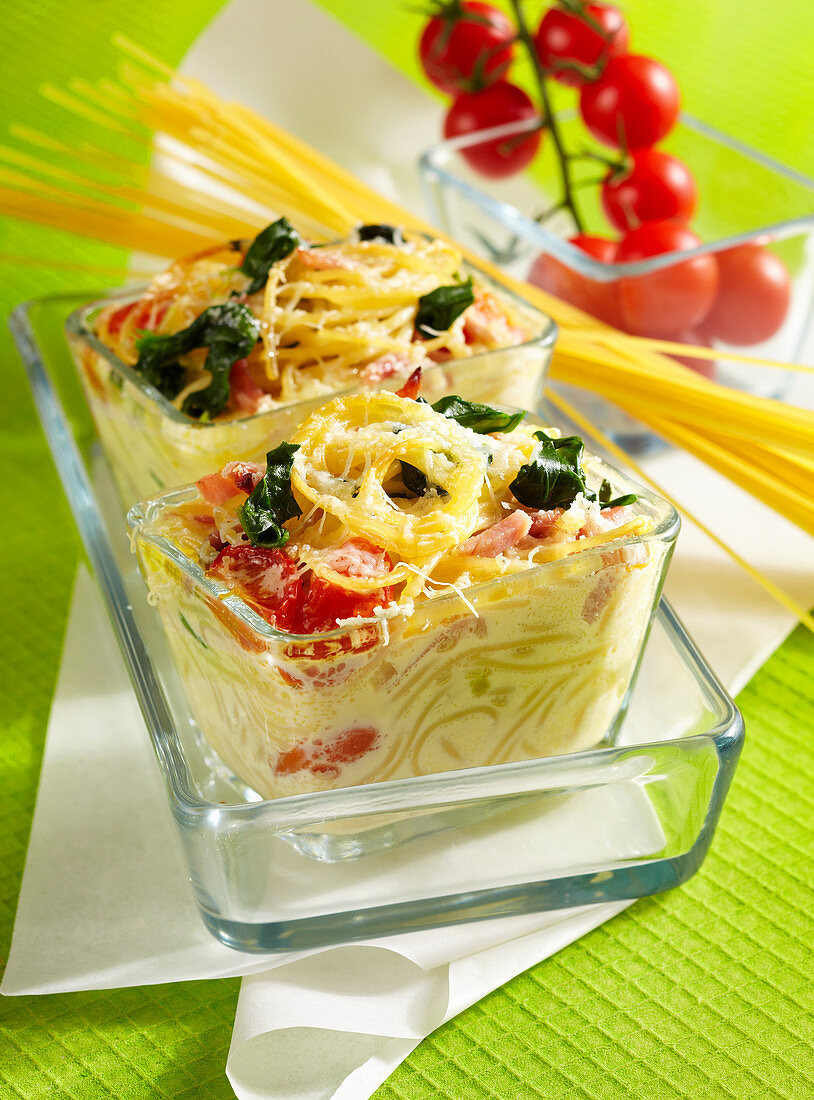 Colourful baked pasta nest with spinach, boiled ham and Parmesan