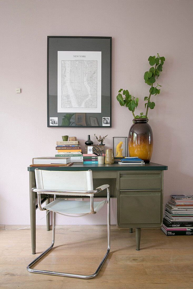 Schwingstuhl und alter Schreibtisch vor rosafarbener Wand