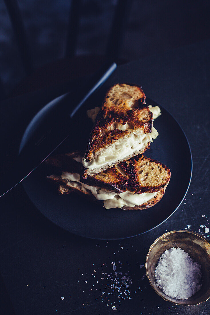 Toasted macaroni and cheese sandwiches with truffles on a dark plate