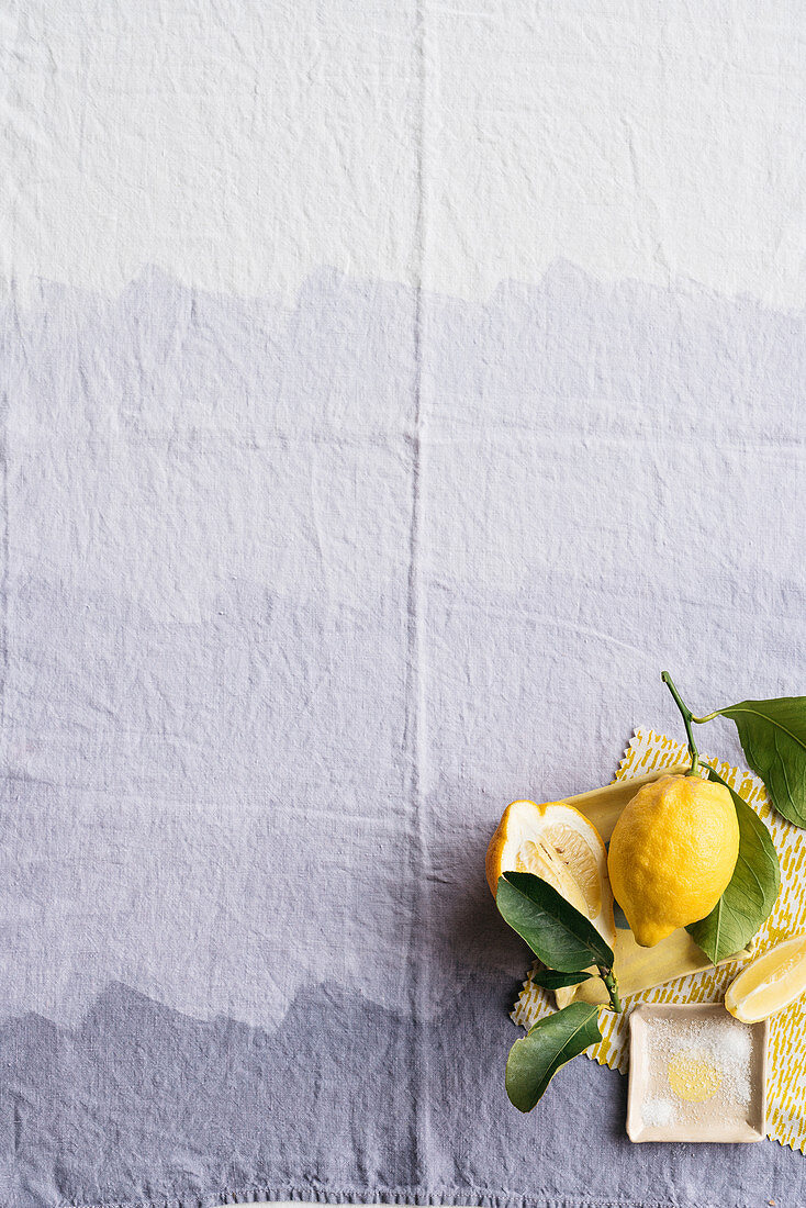 Zitronen mit Blatt auf lilafarbener Tischdecke
