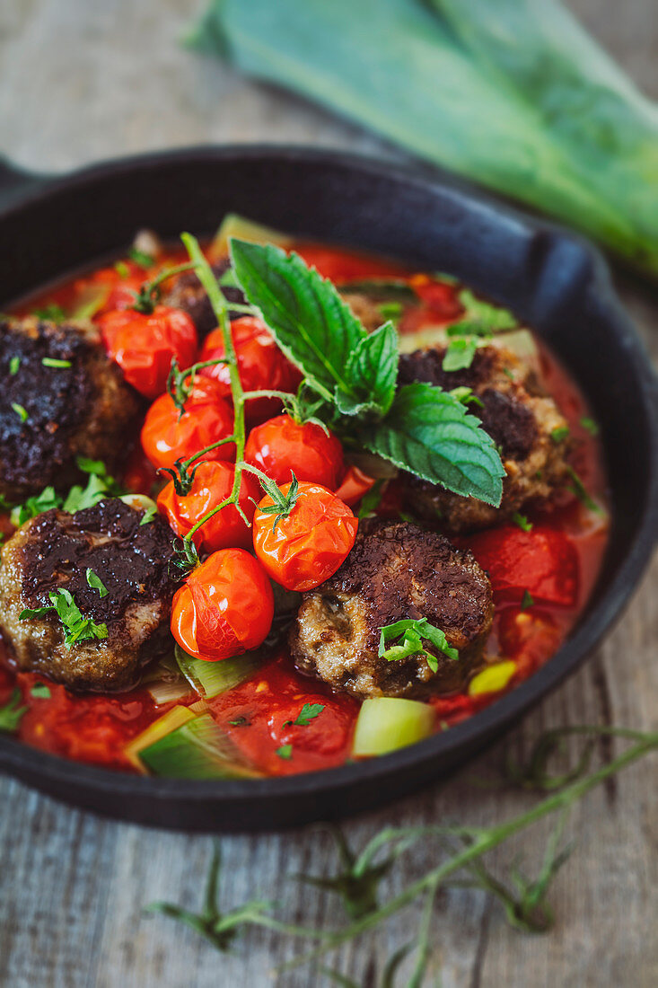 Meatballs with tomato sauce and mint in a cast iron pan