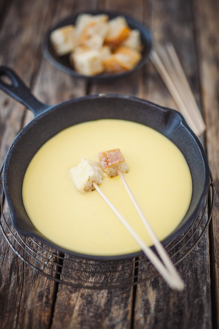 Cheese fondue with white bread in a cast iron pan