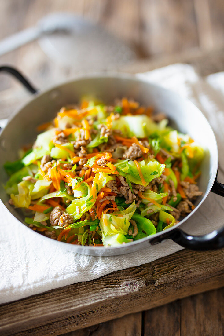 Nappa cabbage and shredded carrots with ground sausage in a pan