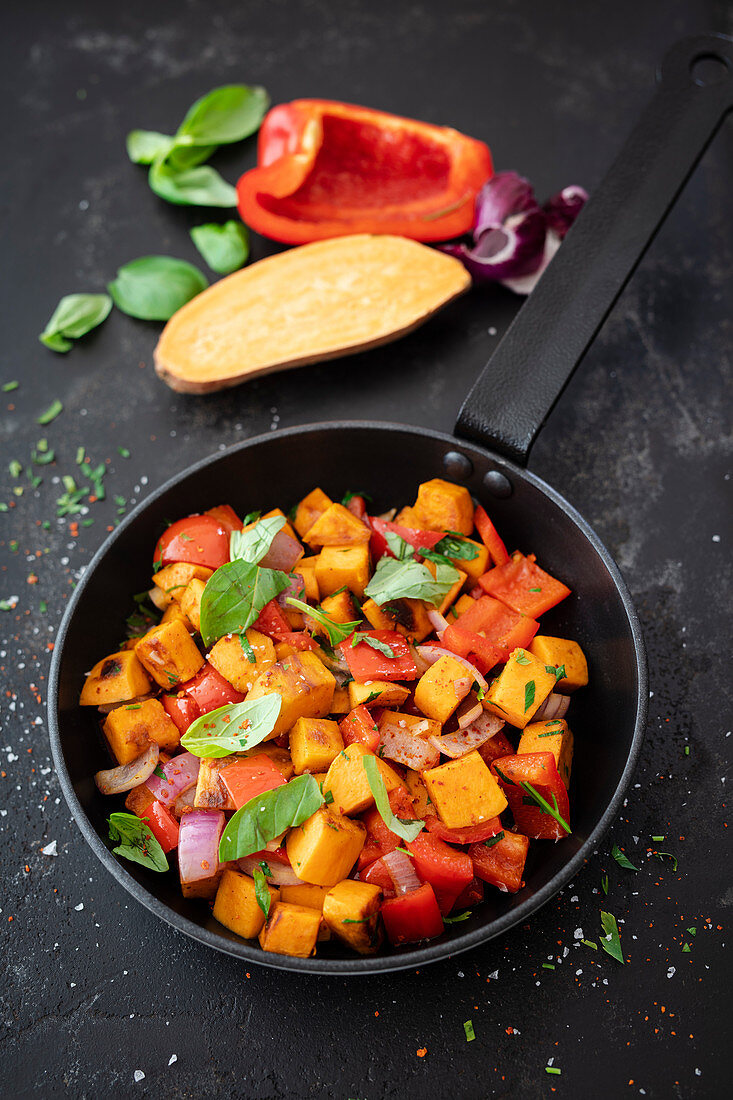 Sweet potato, sweet peppers, and red onion in a pan