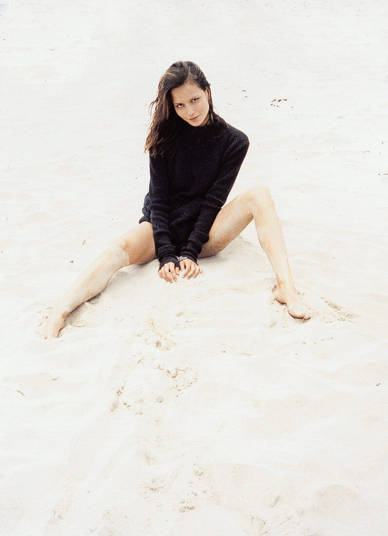 Junge Frau in schwarzem Pulli am Strand