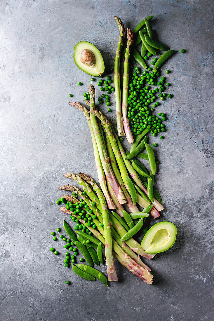 Gepalte Erbsen, grüner Spargel, Erbsenschoten und Avocado (Aufsicht)