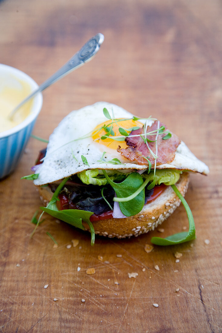 A fried egg, bacon, cress and mayonnaise on a burger bun