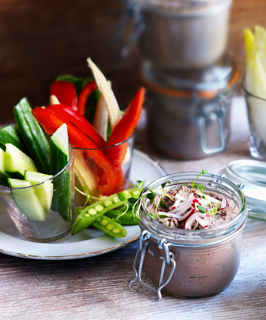 Chicken liver pate in a glass jar with vegetable sticks