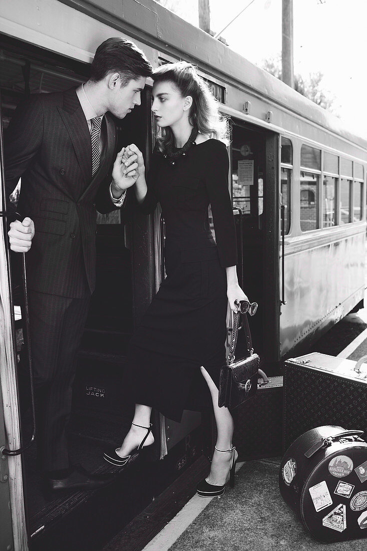 A young couple holding hands by a train (black-and-white shot)