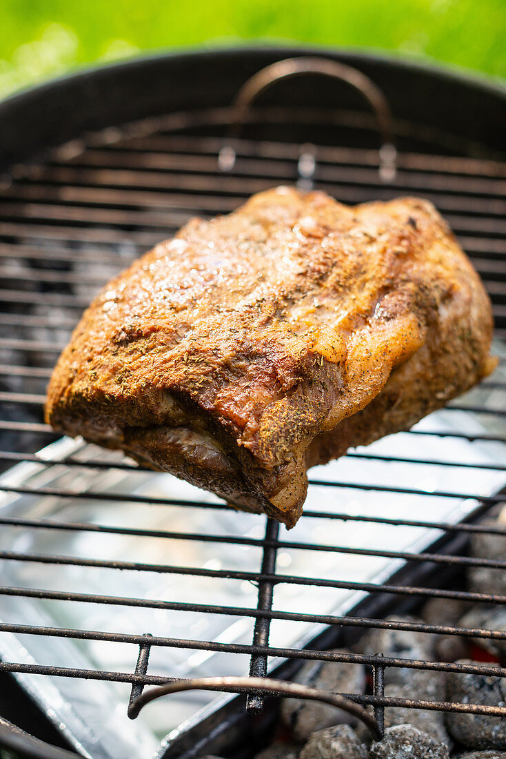 Spiced pork collar on a BBQ for making pulled pork