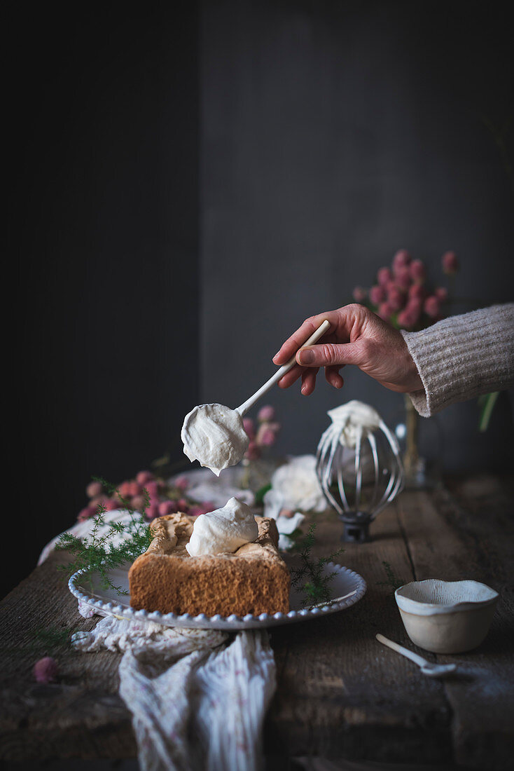 Frau gibt Schlagsahne auf kastenförmigen Biskuitkuchen