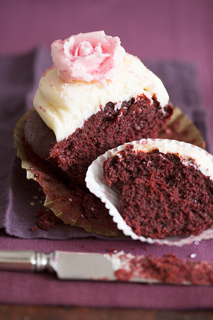 Half a chocolate cupcake with vanilla cream and a sugar rose