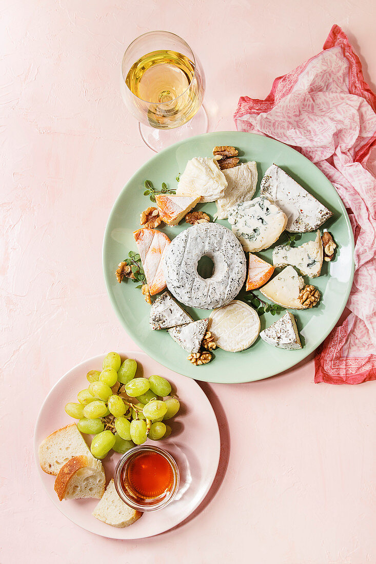 Französische Käseplatte serviert mit Honig, Walnüssen, Brot, Trauben und Wein