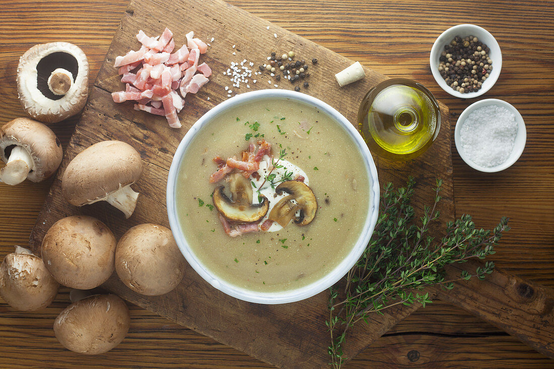 Cream of mushrooms soup with ingredients on a wooden surface