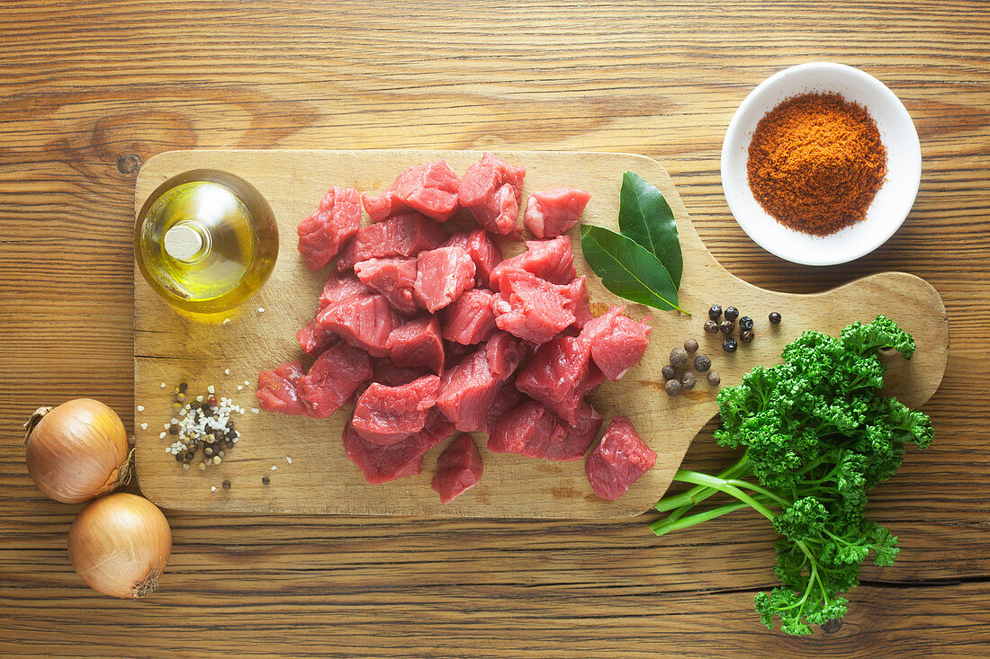 Raw ingredients with beef goulash on a wooden surface