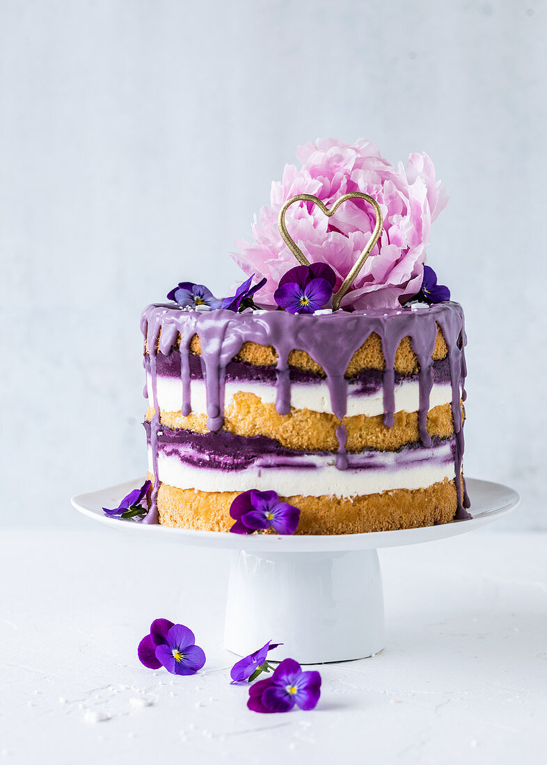 A blueberry drip cake decorated with a peony