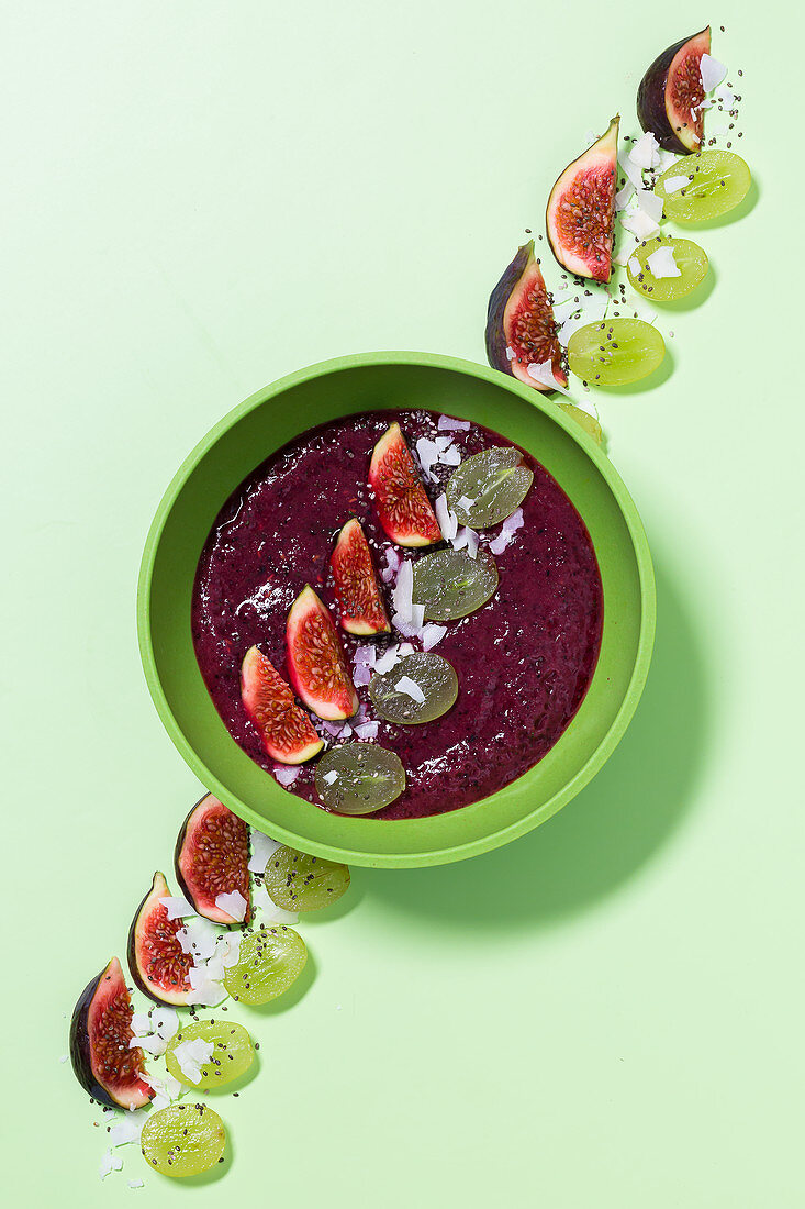 A purple bowl with figs, grapes and coconut chips