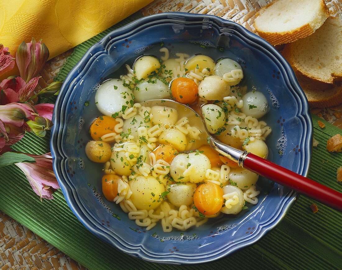 Buchstabennudelsuppe mit Gemüsekugeln in Suppenteller