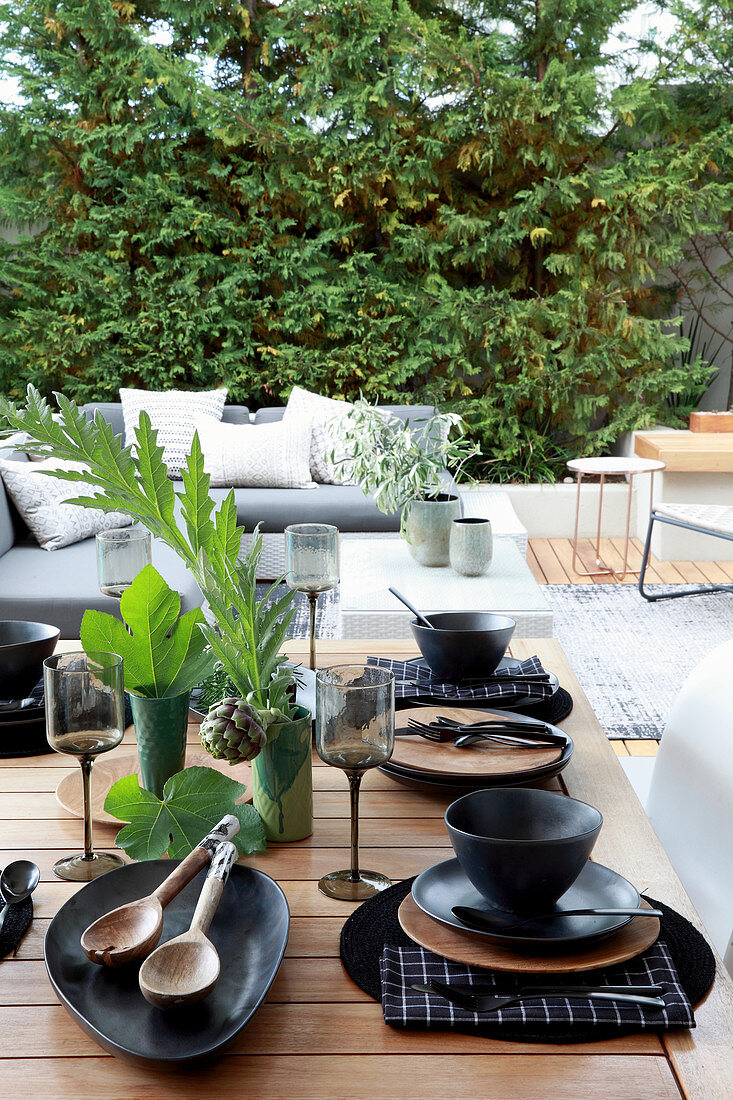 Gedeckter Tisch mit schwarzem Geschirr auf der Terrasse