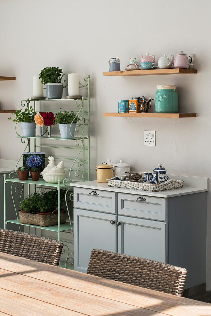 Kitchen base unit, crockery on wall shelves and houseplants on metal shelving unit