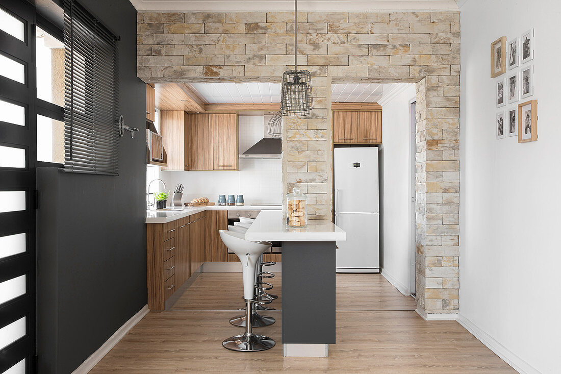 Natursteinwand mit zwei Durchgängen zur offenen Küche