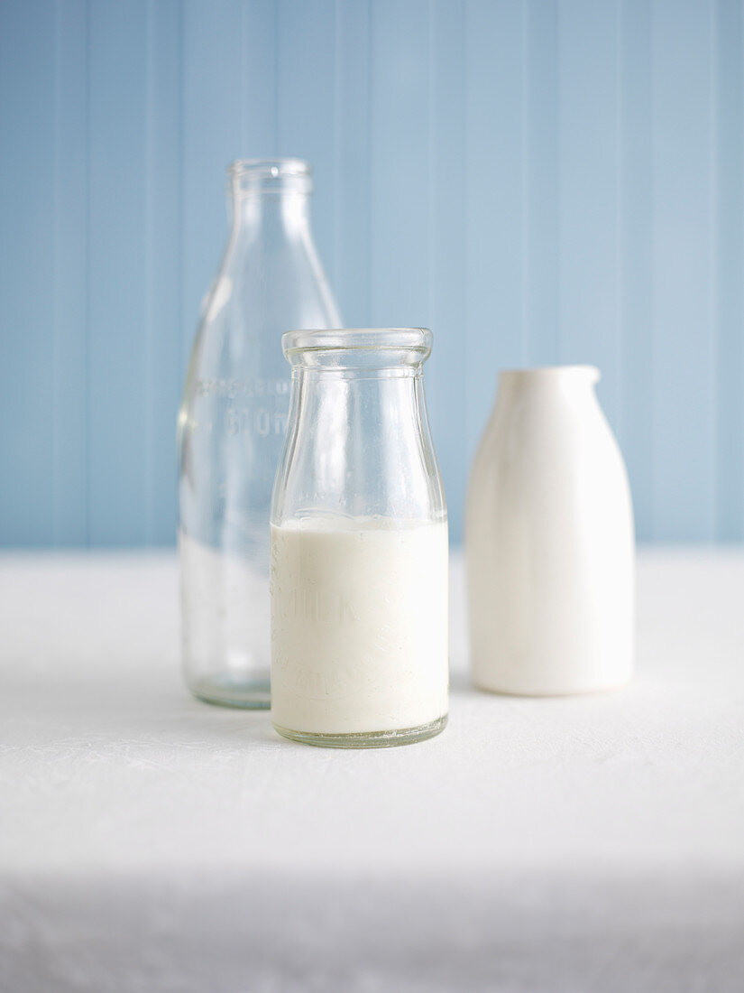 Milch in Glasflasche und leere Behälter