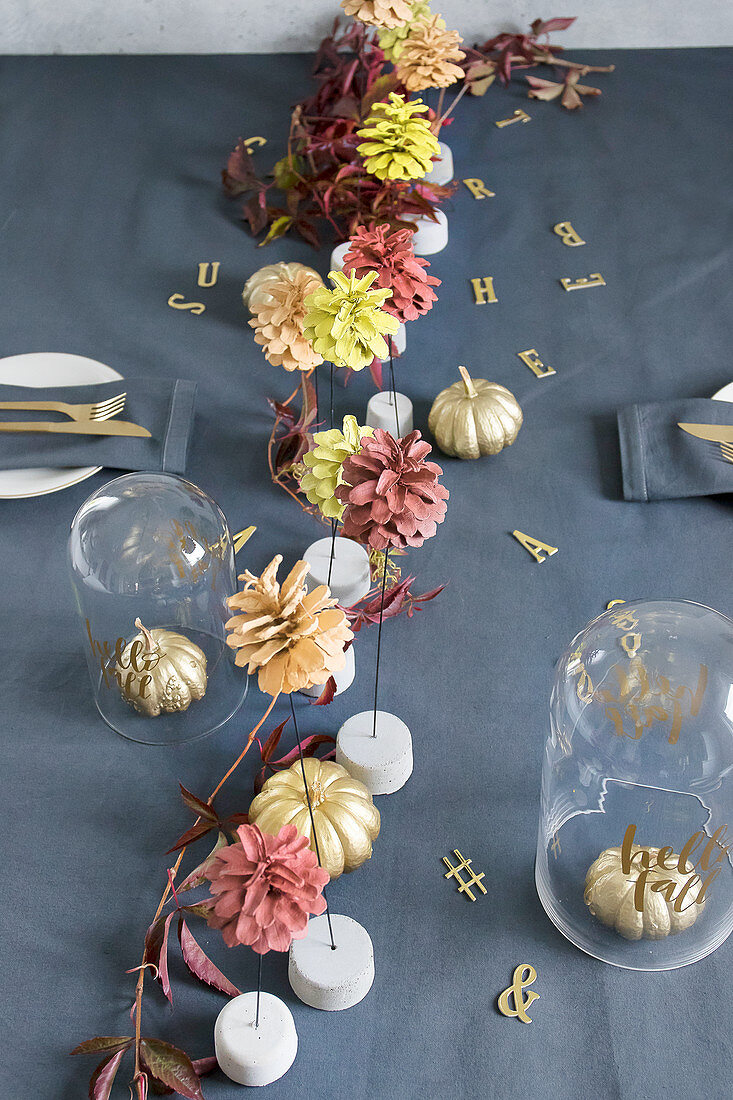 Herbstlich gedeckter Tisch mit bemalten Kürbissen und Zapfen