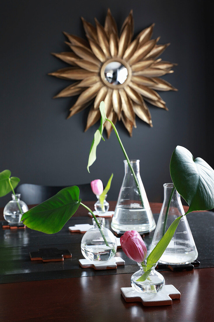 Chemiekolben und Glasvasen mit Blättern und Blumen als Deko