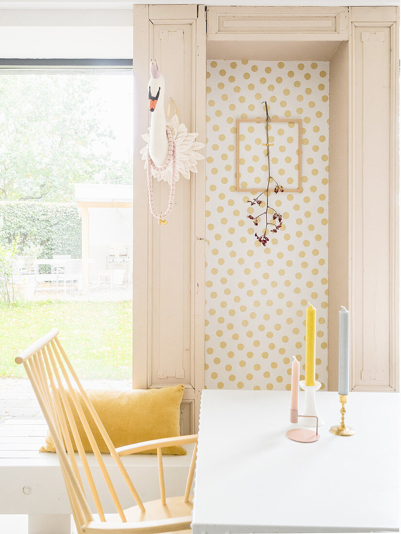 Branch in picture frame on wallpaper with gold polka-dots next to faux swan head on door frame