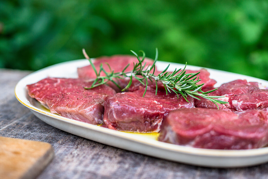 Raw beef loin steaks with rosemary in a garden kitchen