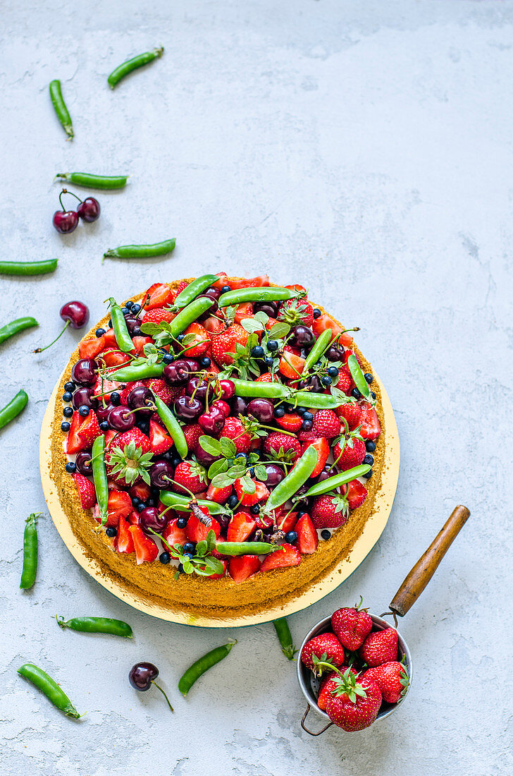 A fruit cake with strawberries, cherries, pea pods and blueberries