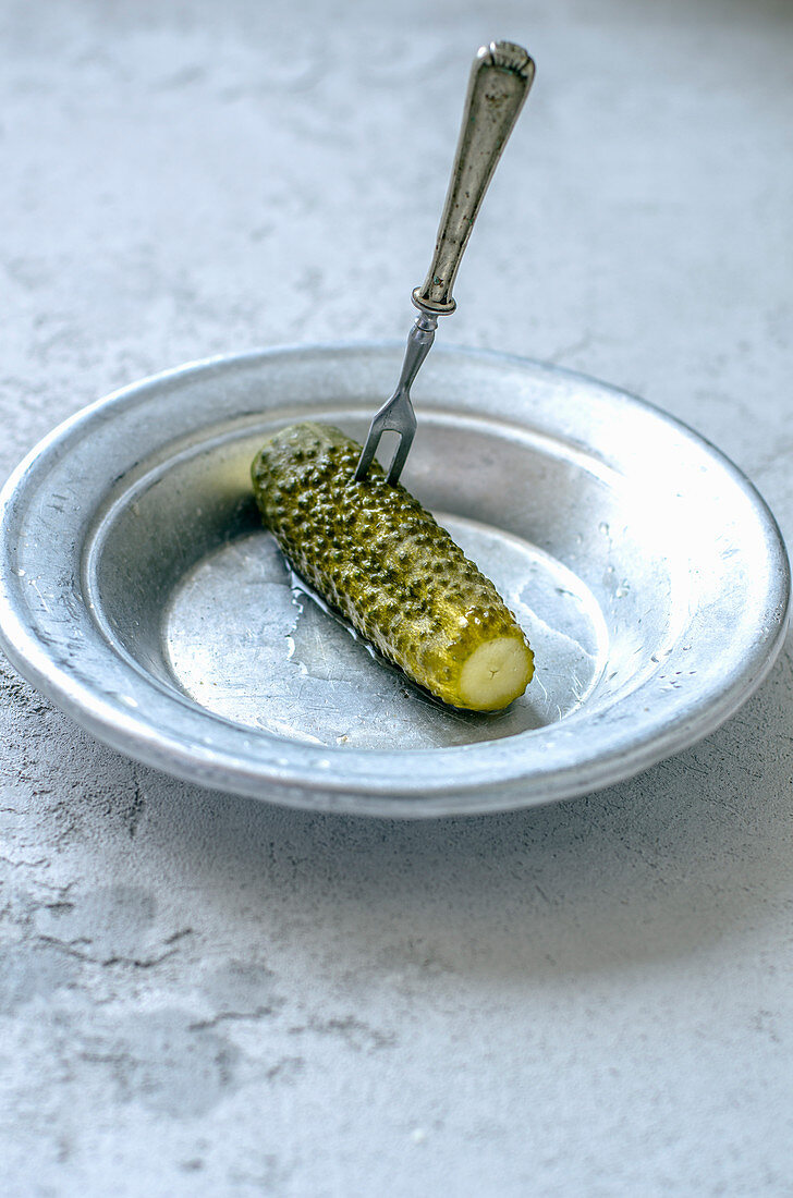 A gherkin with a fork on a plate