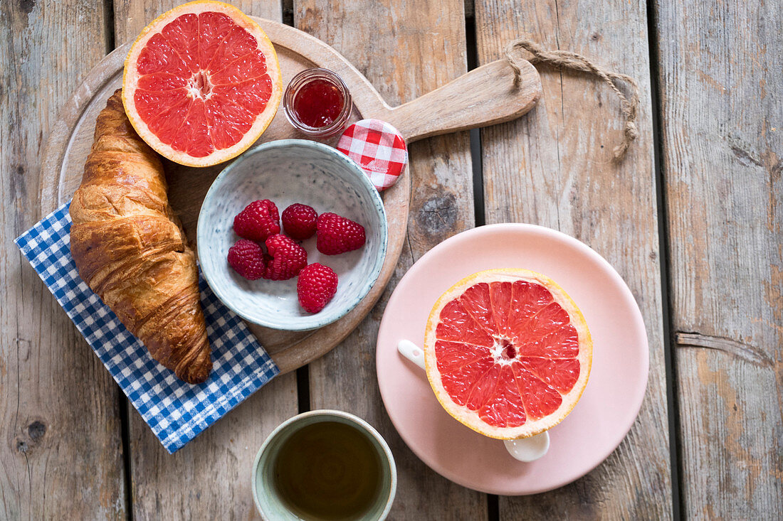 Frühstück mit Croissants, Marmelade, Himbeeren und Grapefruit