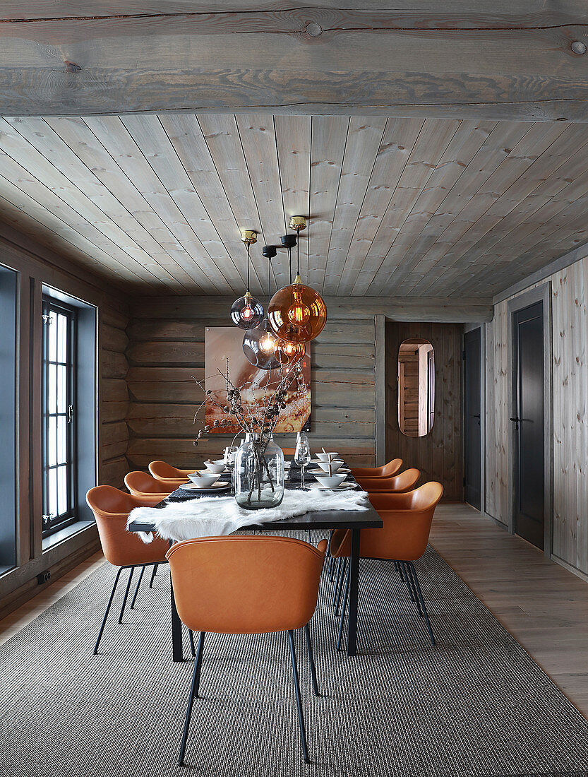 Cognac-brown chairs around set dining table in log cabin