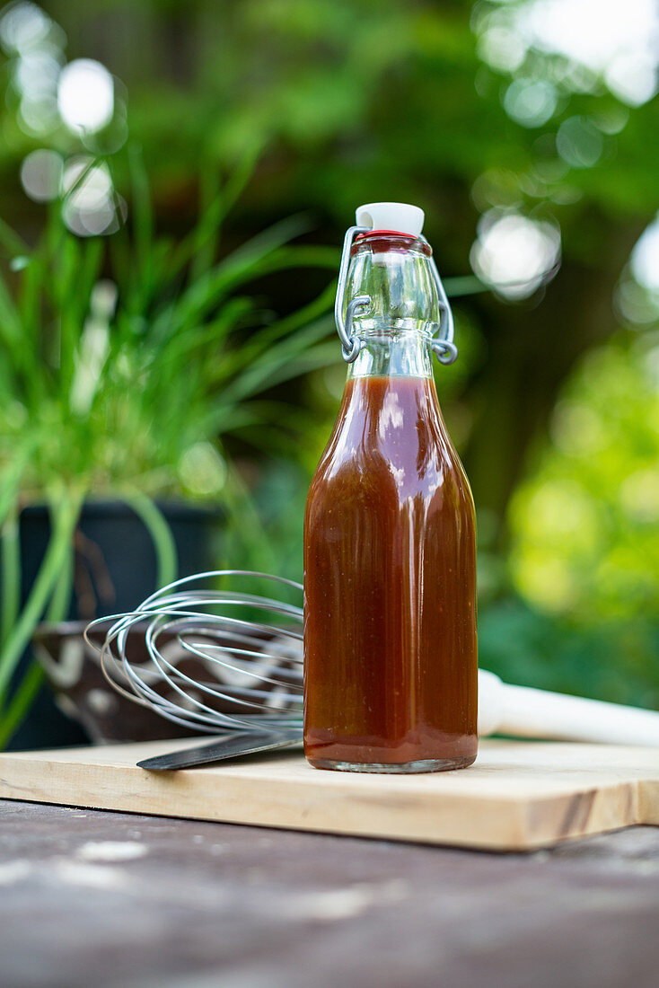 A bottle of homemade barbecue sauce on a garden table