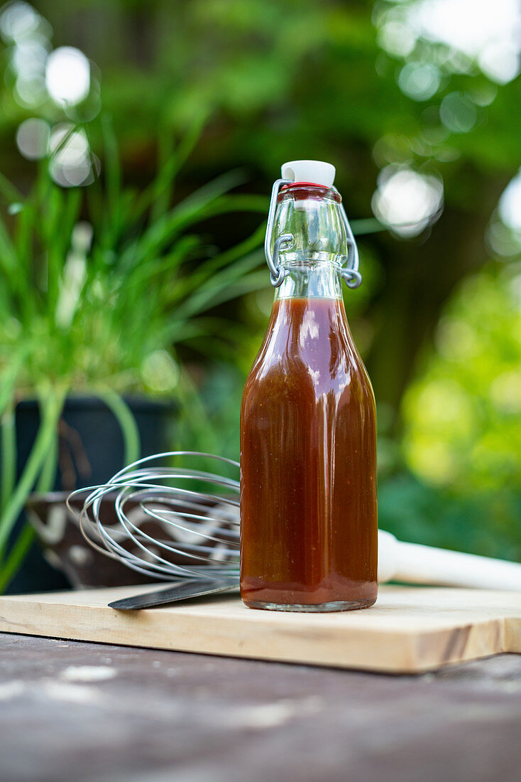 Flasche mit selbstgemachter Barbecuesauce in der Gartenküche