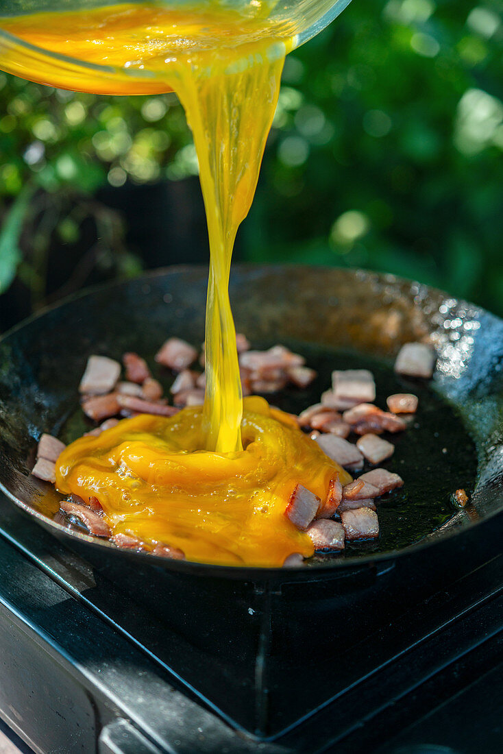 Scrambled eggs with bacon cooking outdoors