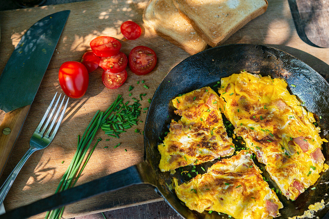 Scrambled eggs with tomatoes, chives and toast on a garden table
